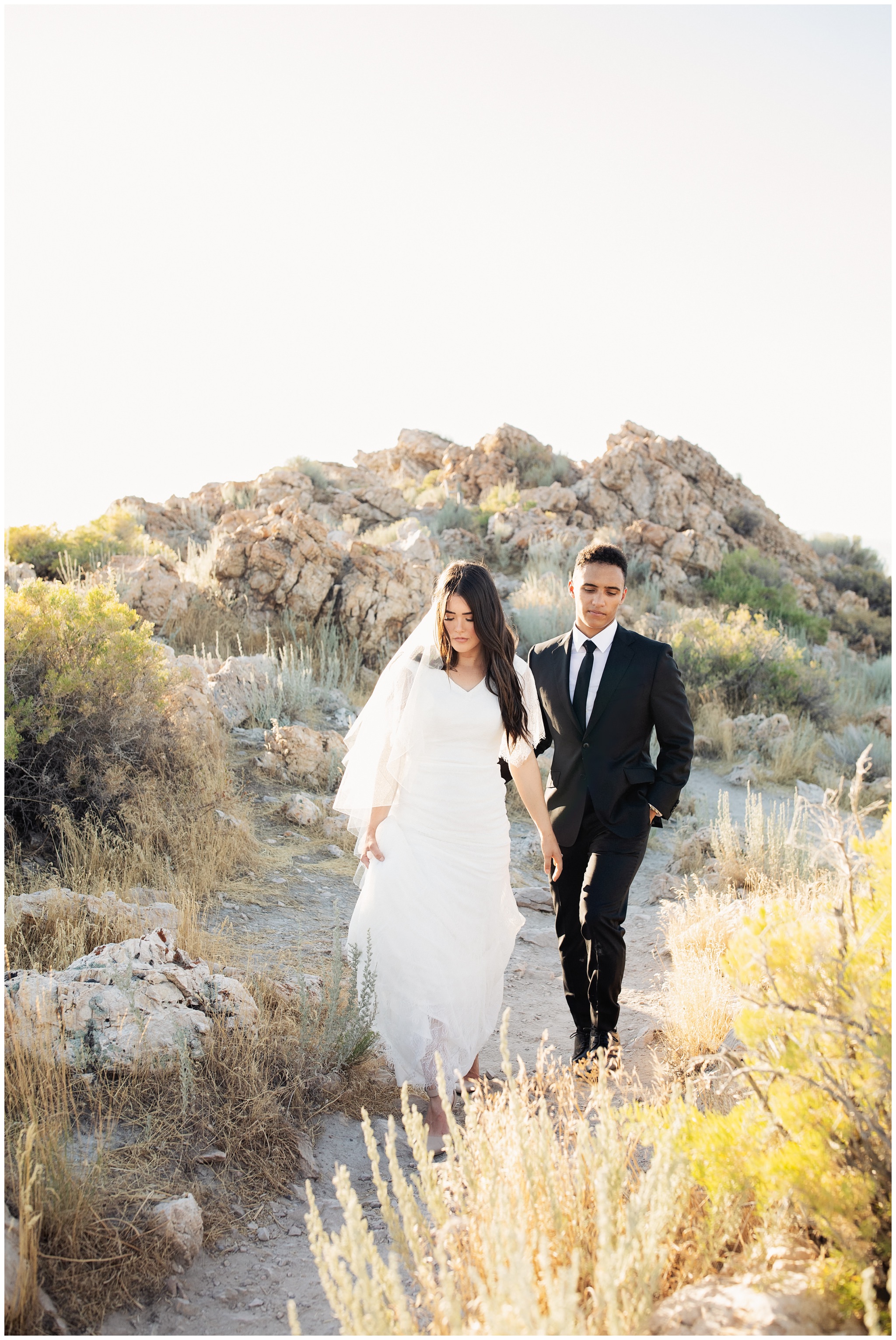 Bride and Groom walking on beach at Antelope island. Rock in the background