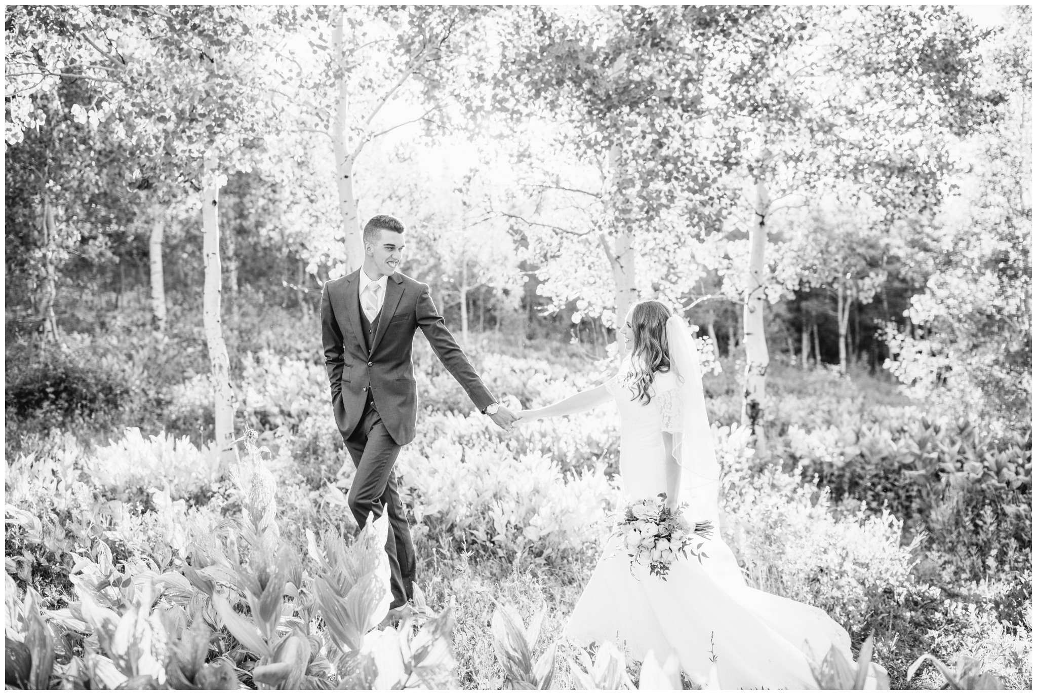 Black and white picture of bride and groom walking in mountains