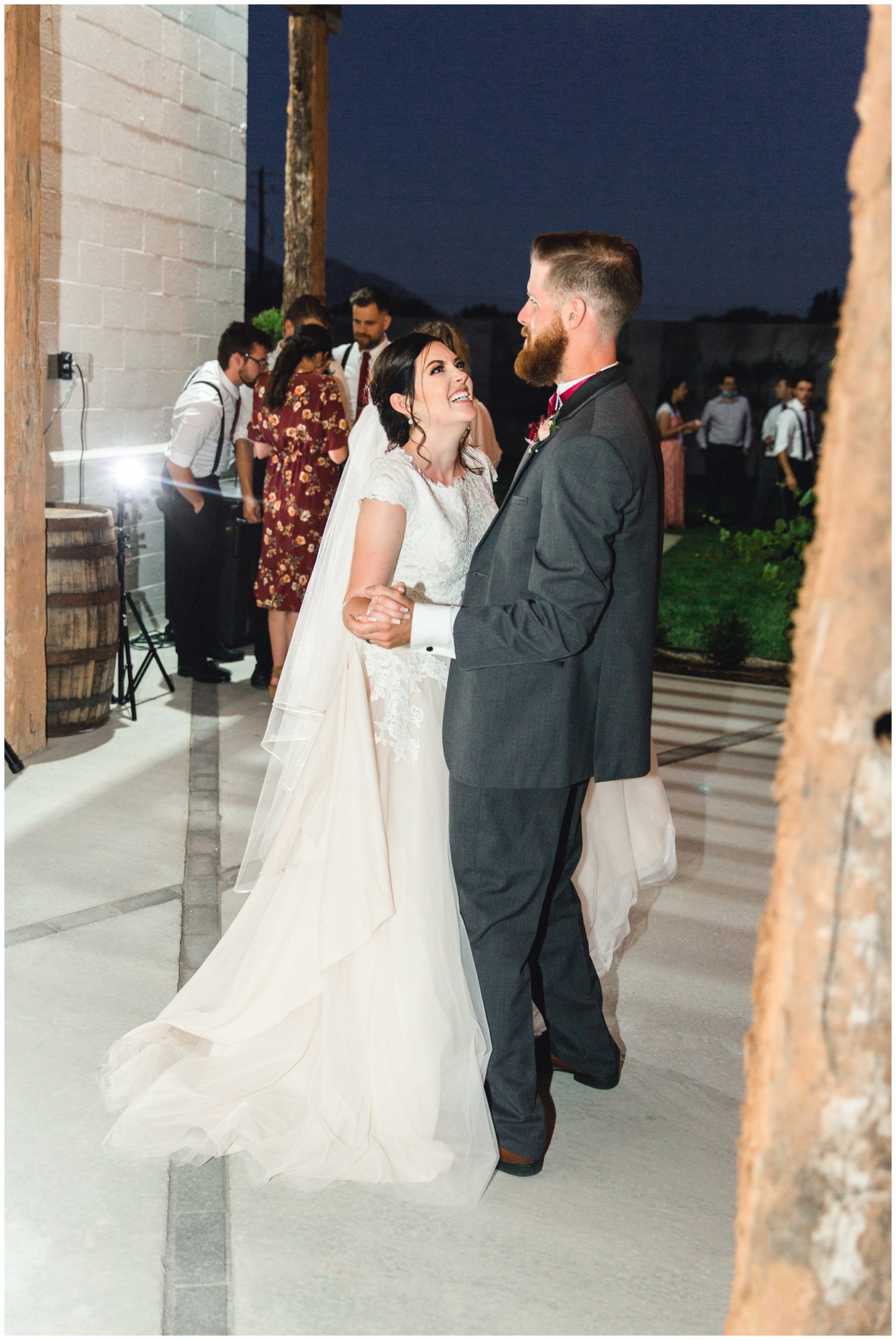 Bride and groom laughing at their wedding reception while dancing together outside of their venue