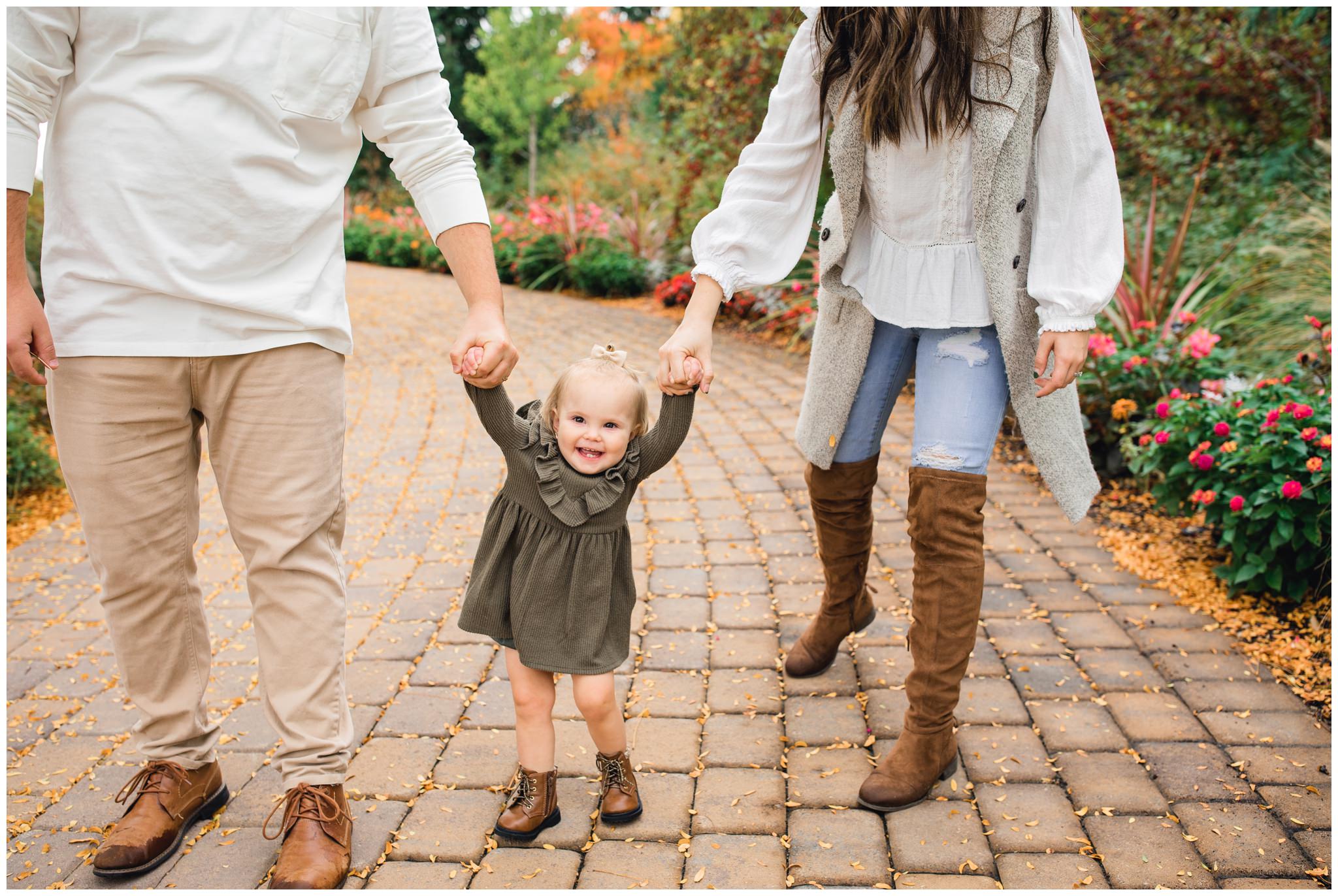 Little baby holding mom and dad's hands while walking