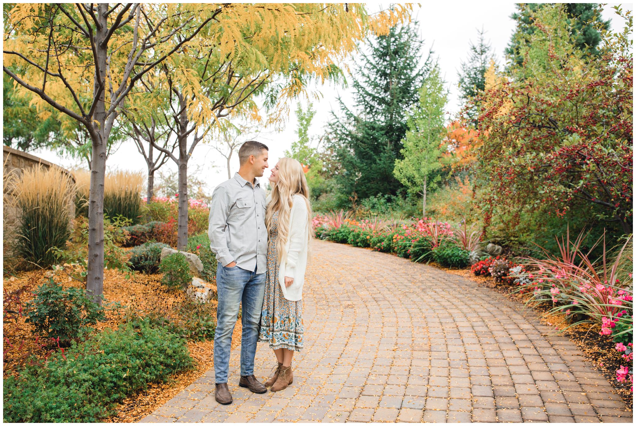 Couple smiling at each other under fall leaves